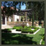 CA Italian garden with terra cotta urn sitting on travertine patio, a fountain and pergola in the background near Pasadena.